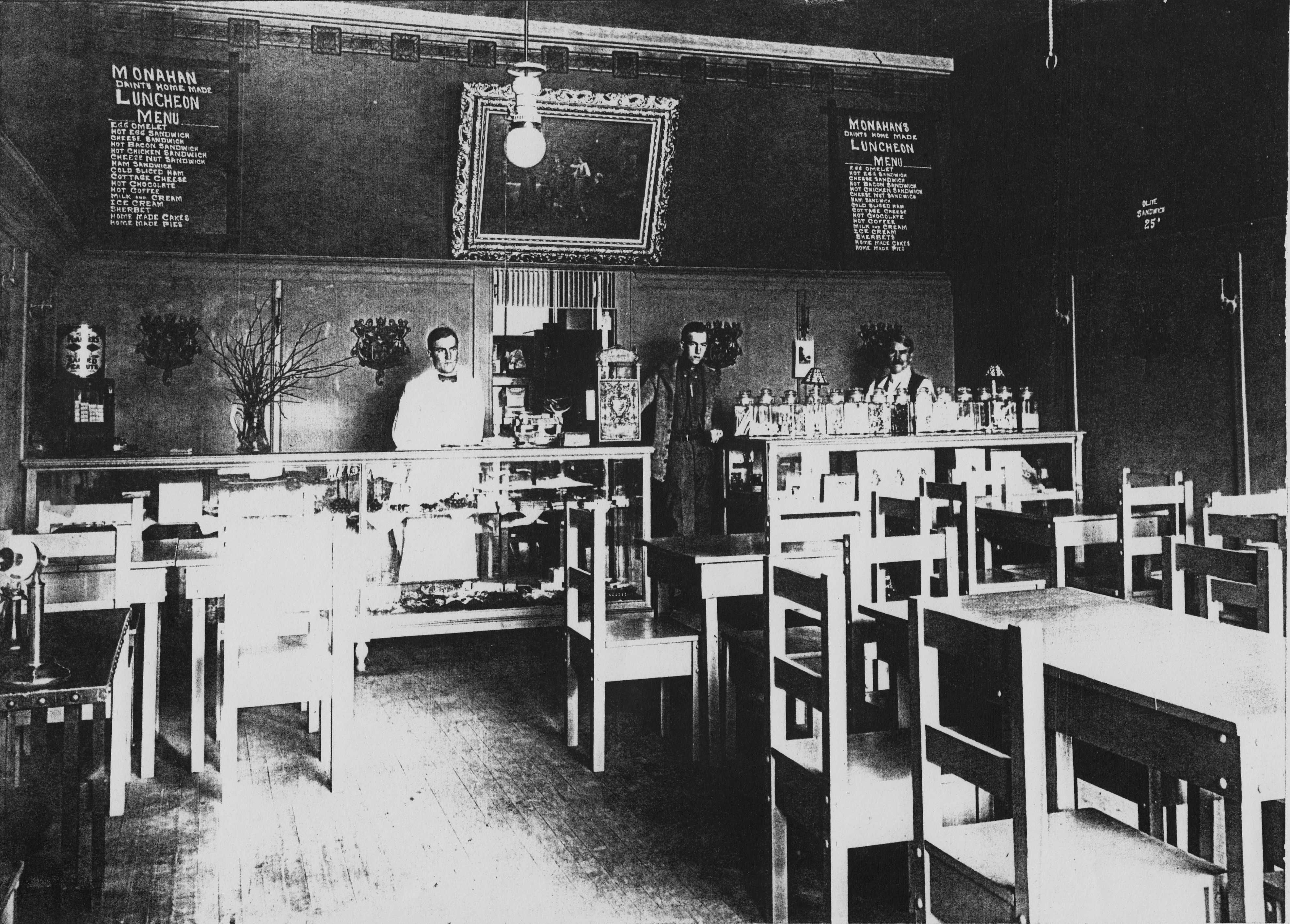 Monahan Chocolate Shop interior, 1910s. Edward Monahan is behind the counter at right. Note the sign with the luncheon menu: customers could order eggs or sandwiches – including a cheese nut sandwich – and pair with hot coffee, hot chocolate or cold milk, to be topped off with ice cream, sherbet, pies or cakes for dessert.