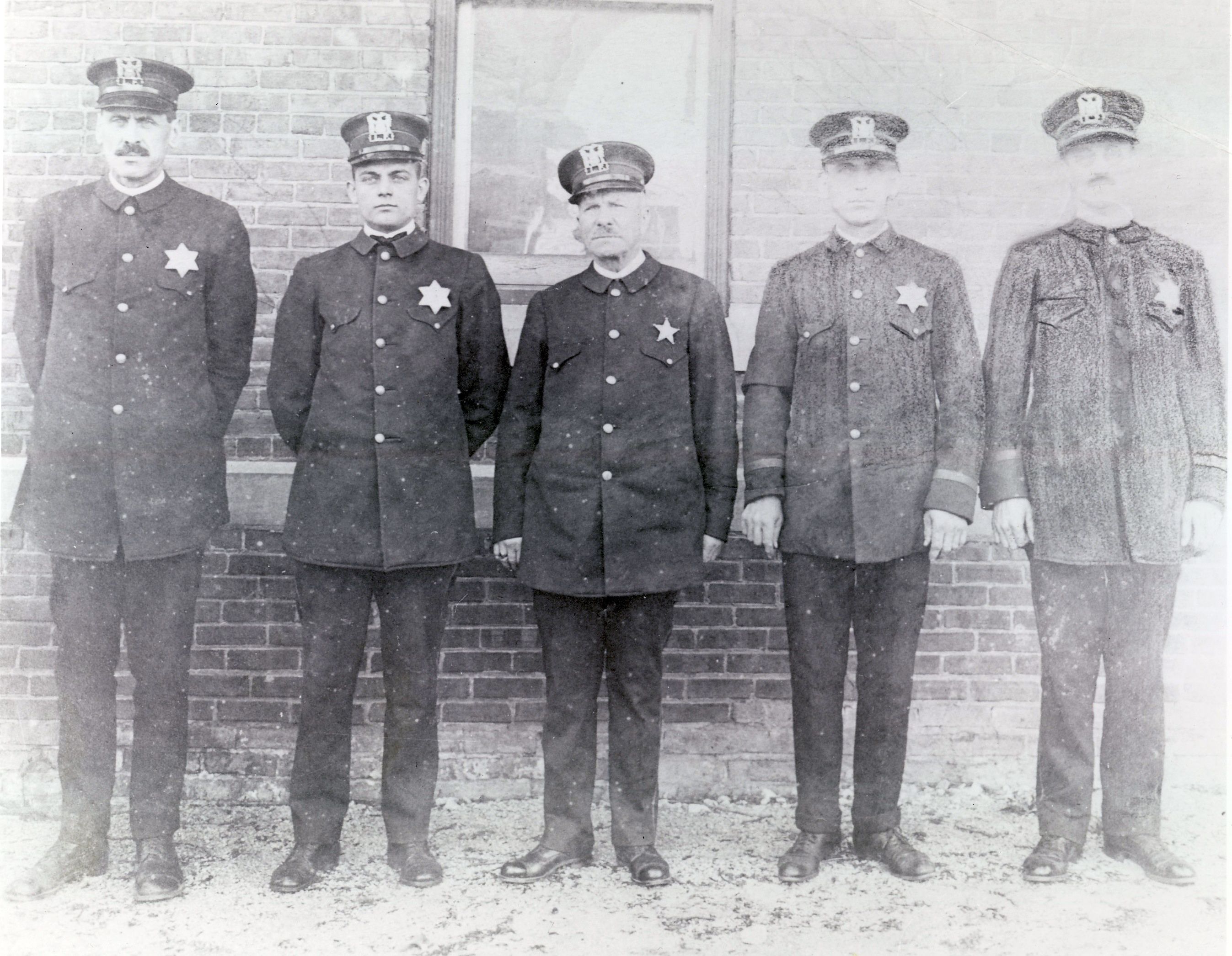 Lake Forest police department, c. 1917. Historically this was a tricky time for law enforcement: with the increase in automobile use came a corresponding rise in speeding, accidents, and car thefts. A January 1917 issue of the Lake Forester describes a hit-and-run accident in Highland Park where the perpetrators ran into a car driven by Sergeant Potter of Fort Sheridan and then raced away to the north. The police in Lake Forest were notified of the crime via telephone. According to the account, “Policeman Berghorn spotted them on McKinley road but they refused to stop when ordered. At the bend in the road on the north edge of town Berghorn ran up beside them, caught hold of the machine, and put them under arrest. In trying to turn their machine they ran it into a tree and tipped over.” No one was hurt – Ferdinand Berghorn turned the criminals over to the Highland Park police.