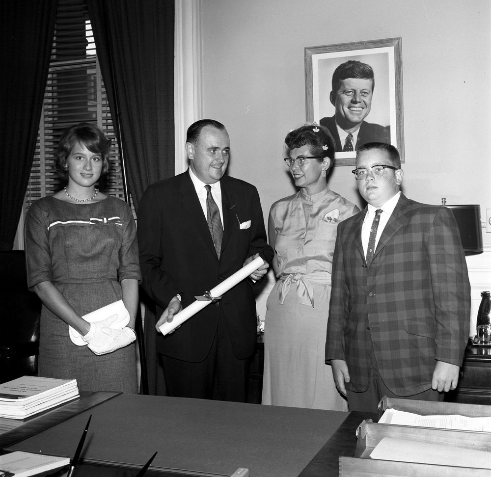 Newly-appointed Director of Food for Peace, Richard W. Reuter (center left), visits with his wife, Margaret Steinorth Reuter, and children at his swearing-in ceremony. Executive Office Building, Washington, D.C. August 1, 1962. Image source: Robert Knudsen. White House Photographs. John F. Kennedy Presidential Library and Museum, Boston. JFKWHP-KN-22990.